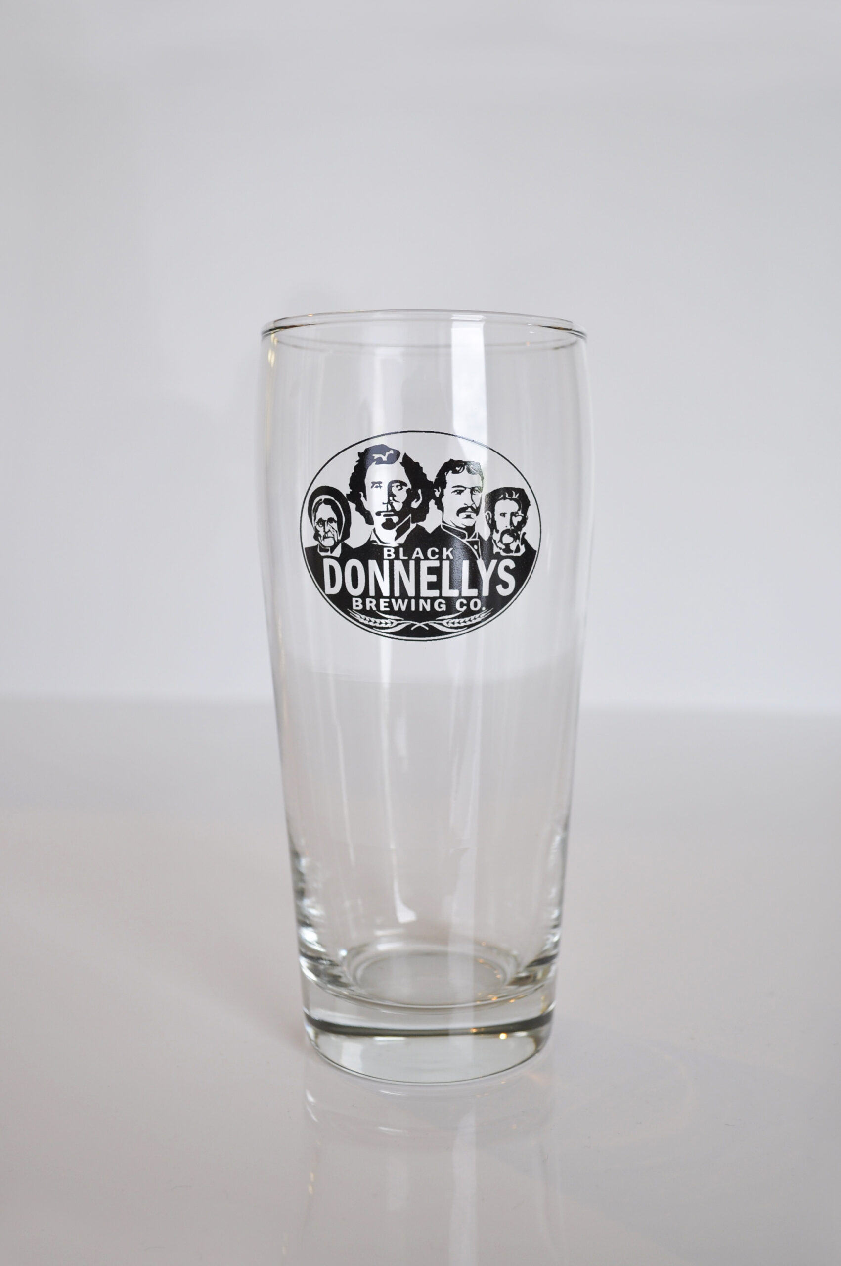 A tall Black Donnellys Brewing Company beer glass decorated with the company logo.